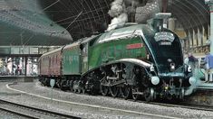 an old fashioned steam train is on the tracks at a station with people standing around