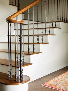 a set of stairs with wooden handrails next to a rug on the floor