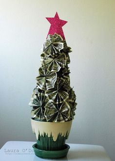 a christmas tree made out of dollar bills sitting on top of a potted plant