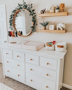 a baby's room with a dresser, mirror and stuffed animals on the wall