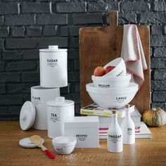 a wooden table topped with white bowls and containers