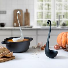 a black swan shaped spoon sitting on top of a counter next to bread and vegetables