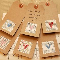 four tags with designs on them sitting on top of sheet music paper and some string