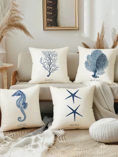 four pillows with seahorses and starfish on them sitting on a rug in front of a couch