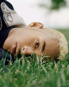 a young man laying in the grass with his eyes closed