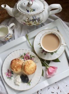 two scones are on a plate next to a cup of tea and saucer