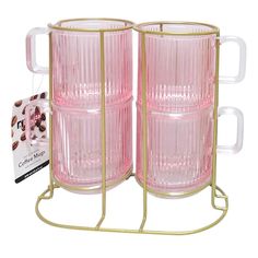 two pink glass mugs sitting on top of a metal stand