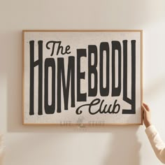 a person holding up a sign that says the homeboy club on it's wall