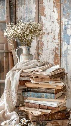 a stack of books sitting on top of a table next to a vase filled with flowers