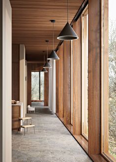 the hallway is lined with wooden paneled walls and windows, along with hanging lamps