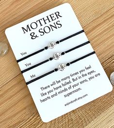 the mother and sons bracelets are set on top of a card next to some stones