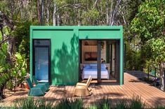 a green shipping container with a bed in it's center surrounded by greenery