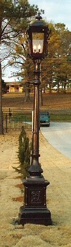 an old fashioned lamp post in the middle of a park