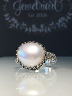 Handmade Pearl Ring. Natural Pearl Ring. Artisan Pearl Ring. Upcycled Pearl Ring. Crown Ring. Unique Pearl Ring. Stunning upcycled pearl and solid sterling silver hand forged medieval ring. Handcrafted with crown bezel and beautifully etched very substantial 10 gauge band. This ring is a size 8 1/2 but can be made to order with a similar pearl🎁🎁 All rings are handmade by me so feel free to contact me with any custom requests. Pearl measures 14mm. Show your Love❤️❤️ on Anniversaries, Birthdays, Artisan Untreated Jewelry For Wedding, Artisan Untreated Wedding Jewelry, Unique Handmade Pearl Ring For Anniversary, Handmade Round Rings In Fine Jewelry Style, Artisan White Ring For Wedding, Elegant Untreated White Jewelry, Unique Handmade Pearl Ring For Wedding, Handmade Vintage Pearl Ring In Sterling Silver, Handmade Moonstone Sterling Silver Wedding Ring