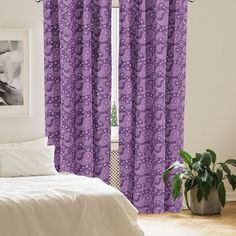 a bed room with a neatly made bed and purple curtains