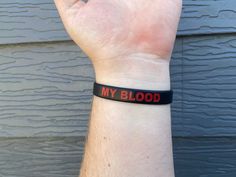 a wristband with the words my blood on it is held up in front of a wall