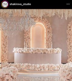 a wedding cake with white flowers and chandelier hanging from it's ceiling