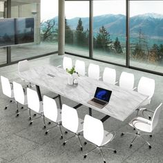 a table with white chairs and a laptop on it in front of large windows overlooking mountains