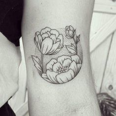 a black and white photo of a flower tattoo on the left arm, with dots in the background