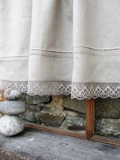 two rocks stacked on top of each other in front of a window with a curtain