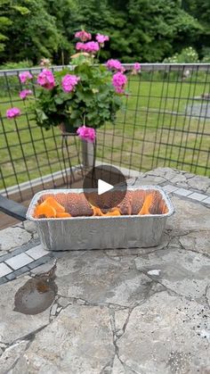 a metal pan filled with oranges sitting on top of a stone table next to a potted plant