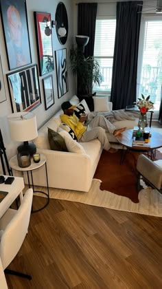 a living room filled with furniture and pictures on the wall above it's windows