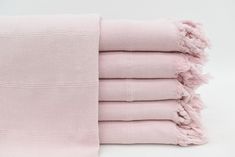 six pink towels stacked on top of each other in front of a white background,