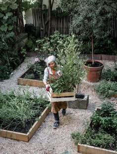 an older woman holding a box full of plants