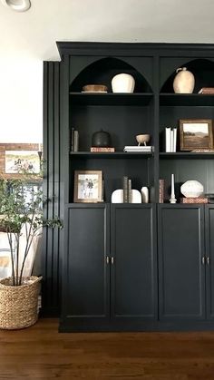 a living room with black bookcases and white vases on top of them