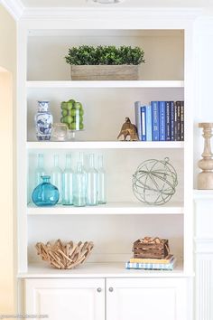 a white book shelf filled with books and vases