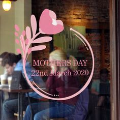 people sitting at tables in front of a window with the words mothers day on it