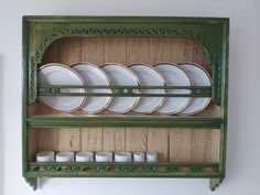 a green shelf with plates and cups on it