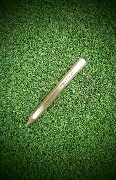 a pen laying on top of green grass with the word, i love you written on it