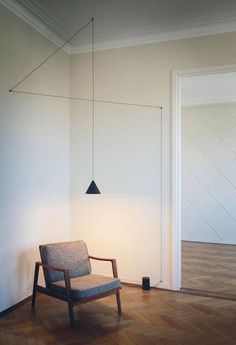 a chair sitting on top of a hard wood floor next to a wall with a light hanging from it