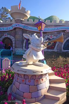 a statue of a pig with a trumpet in front of a flower garden