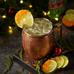 a copper mug filled with ice and garnished with limes, surrounded by christmas decorations