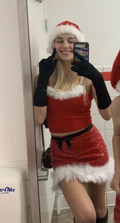 a woman dressed as santa claus taking a selfie in the bathroom with her cell phone