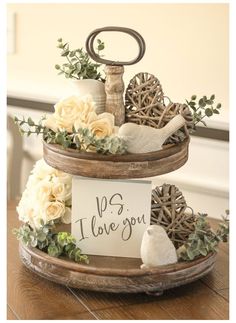 two tiered trays with flowers and signs on them sitting on top of a wooden table