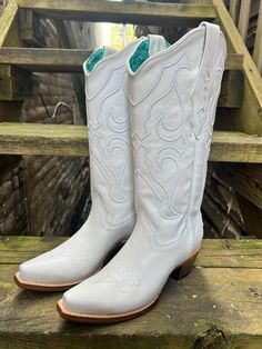 a pair of white cowboy boots sitting on top of a wooden bench