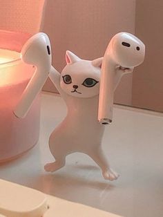 a white cat figurine holding a pink object