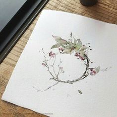 a piece of paper with watercolor paint on it sitting next to a cup and pen