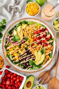 a salad with chicken, avocado, tomatoes, corn and lettuce