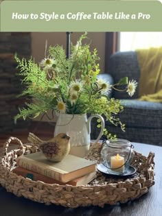 a tray with flowers, candles and books on it sitting on a table in front of a couch