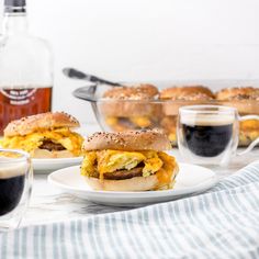 two plates with sandwiches on them next to some cups and glasses filled with liquids