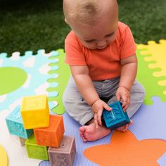 a baby sitting on the ground playing with blocks