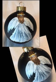 two black and white christmas ornaments with angel wings on one ornament, the other in gold