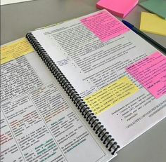 an open notebook with sticky notes attached to it and some pens on the desk next to it