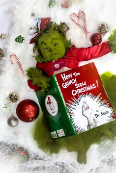 the grinch doll is laying next to a christmas book