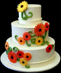 a three tiered cake decorated with flowers and swirls on a black tablecloth