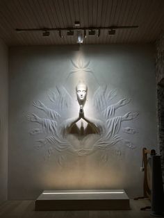 a large white wall with a buddha statue on it's face and hands in the center